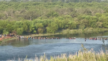 画面曝光：数百名非法移民涌入美边境 背着孩子行囊趟水过河